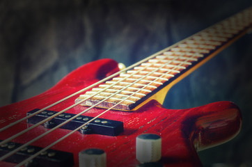 Close-up red bass guitar on dark background. Vintage toning with vignette