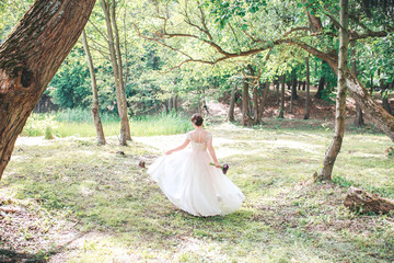 Beautiful bride in vintage white dress walking in the park.
