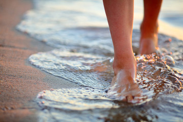 Fototapeta Female feet step on the sea wave obraz