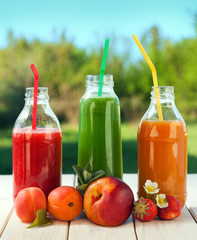 glass of detox smoothie and fruit on wooden table in the garden