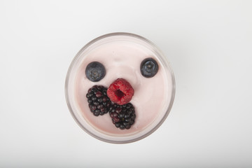 glass of fresh berries and yogurt isolated on white background