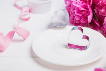 Two hearts on the plate and pink peonies.