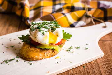 Sandwich with poached egg and tomato on a cutting board