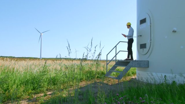 The engineer is standing on the steps of a windmill.