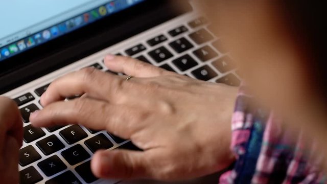 Woman writes on her computer, close