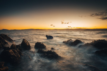 Fototapeta na wymiar Waves against the rocks in Eastbourne, New Zealand