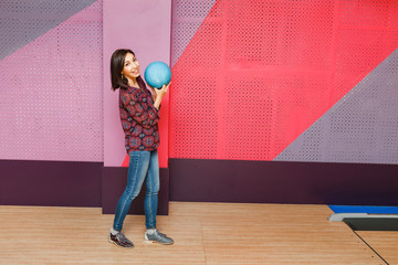 Beautiful young asian woman holding bowling ball and looking at the camera.