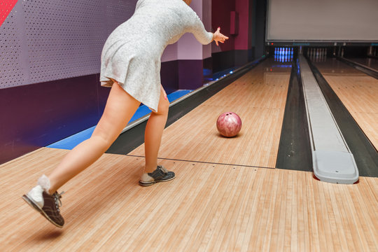 A woman in a bowling club throws a ball on the path in the hope of knocking out a strike