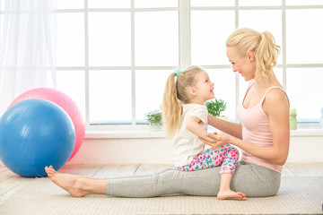 Young mother and daughter exercise together indoors