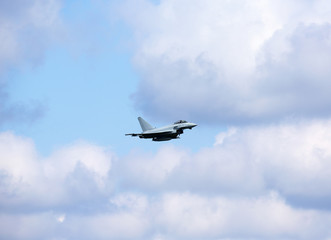 Fototapeta na wymiar Jet fighter against the cloudy and blue sky.