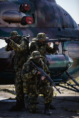 Photos of a group of military men with a gun in front of a helicopter