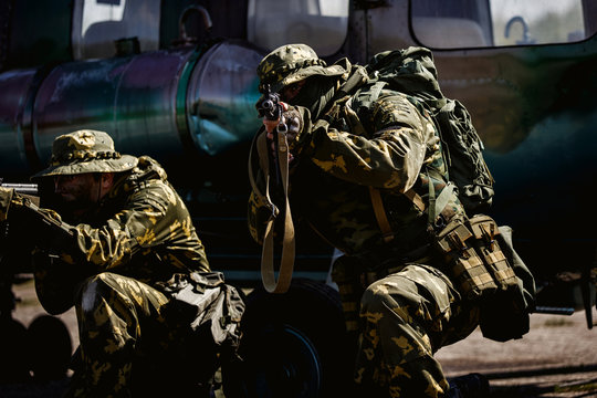 Photos of a group of military men with a gun in front of a helicopter