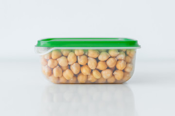 Wet chickpeas kept in plastic container in the kitchen with the water drops on the white background