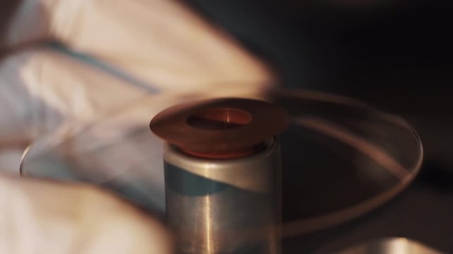 Worker hand in rubber gloves put magnifier lens on vacuum tube at manufacture, close up