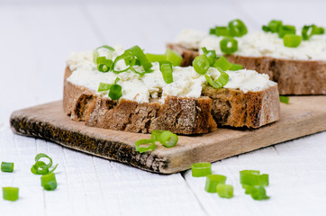 Bread with butter and spread. Concept of healthy breakfast. Spring onion, Vegetables. Wooden white table with copy space