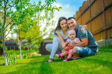 Fototapeta premium happy family plays on a lawn near the house, embrace and smile