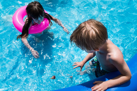 young girl and boy in pool looking at dive toy