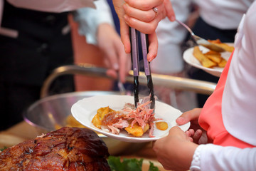 waiter serves roasted meat and baked potatoes at the party