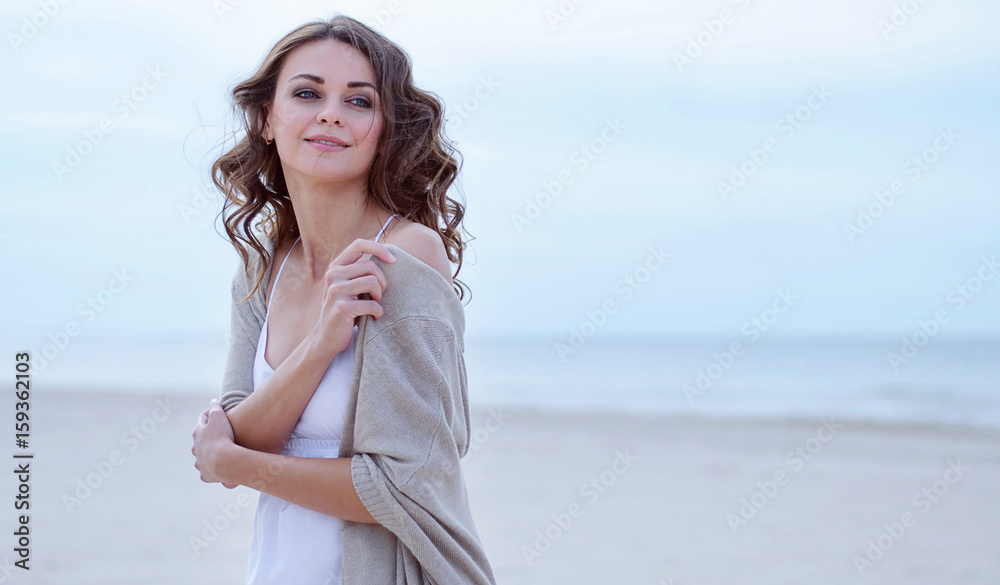 Wall mural woman face portrait on the beach. happy beautiful curly-haired girl close-up, the wind fluttering ha