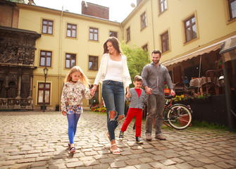Obraz na płótnie Canvas Young family with children on walk the street of tourist city