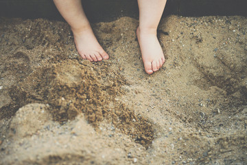 cute baby feets in sandbox close up