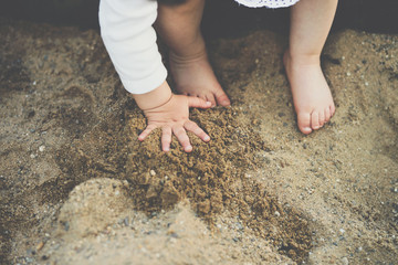 cute baby feets and hand in sandbox close up