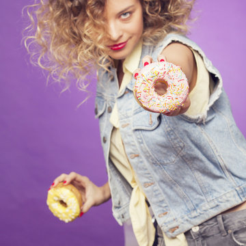 cute girl demonstrating a sweet donut on the purple background