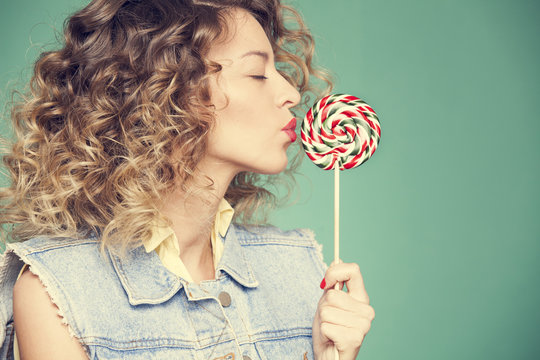 cute young girl kissing a candy on a wand