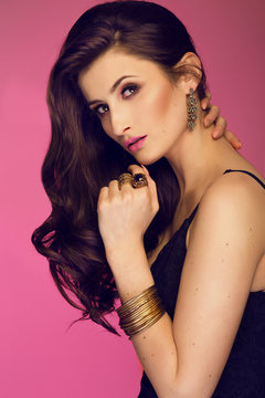Sexy young brunette looking at the camera, pink background studio shoot