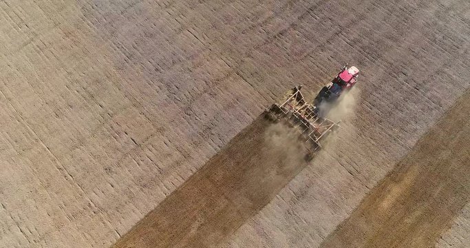 Tractor cultivating striped field in Springtime, aerial view.
