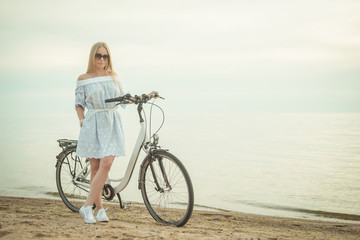 Fototapeta premium Summer. Beautiful woman with bicycle at the seaside