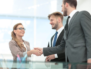 Happy smiling business people shaking hands after a deal in offi