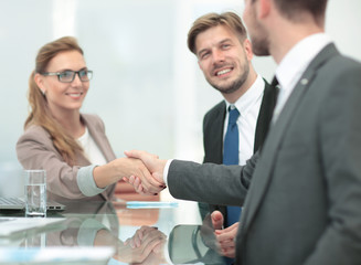 Happy smiling business people shaking hands after a deal in offi