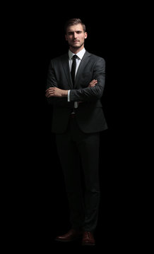 Handsome business man isolated on black with arms crossed