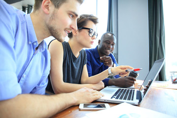 Teamwork,brainstorming concept.Young creative managers team working with new startup project in modern office. Contemporary notebook on wood table.Horizontal, film effect