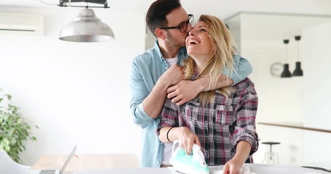 Young couple at home doing hosehold chores and ironing