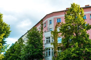Fototapeta na wymiar pink apartment building at prenzlauer berg with green treetops