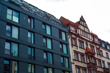 Fototapeta premium black modern building next to very old brick house