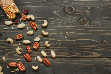 Healthy bar with nuts and seeds on the wooden background, top view. Copy space