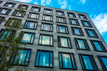 grey facade finance building with cloud reflections in the big blue windows