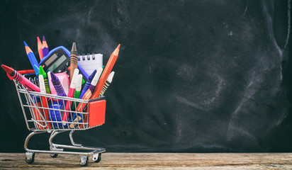 School shopping cart on blackboard background