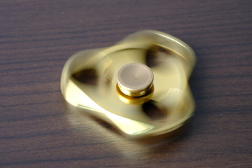 Golden metal fidget spinner spinning on table