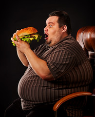 Diet failure of fat man eating fast food hamberger. Happy overweight person spoiled healthy food by...
