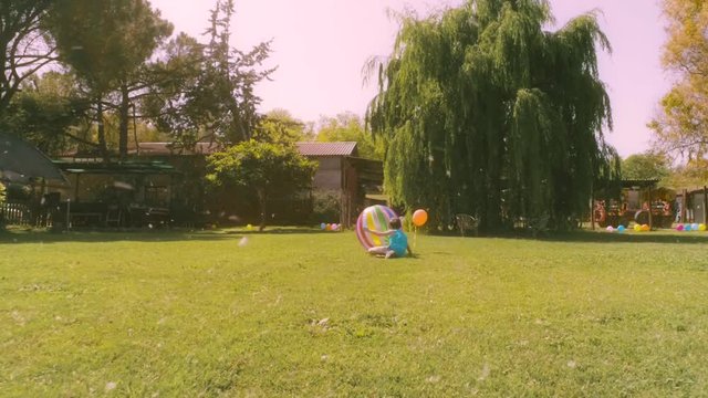 Two little girls playing with big coloroful ball at the countryside