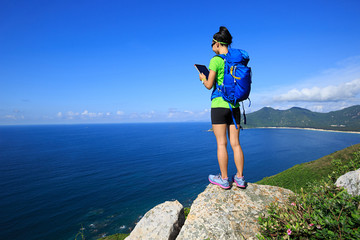 successful woman backpacker use digital tablet on seaside mountain rock