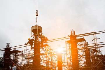 Silhouette construction industry team safely to work load concrete building according to set goal over blurred background sunset pastel for industry background.