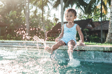 kid play with water in the swiming pool