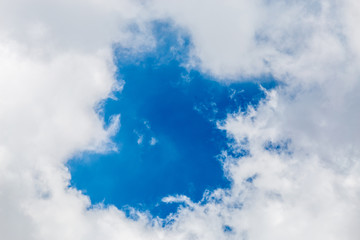 Natural cloudscape. Blue sky in center with fluffy clouds as the frame background.