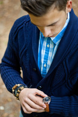 Fashion portrait of young businessman handsome model man in casual cloth suit with accessories on hands, steel watches,grey jeans and bracelets