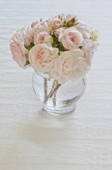 Obraz na płótnie Canvas Pink Roses in vase on white tablecloth/Arrangement of wild pink roses in vase on white tablecloth